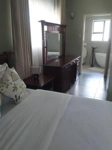 a bedroom with a bed and a television and a bathroom at Beautiful No Fuss Serene 4-Bed House in Bulawayo in Bulawayo