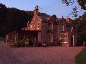 an old stone house with flowers in front of it at Kilmichael House in Drumnadrochit