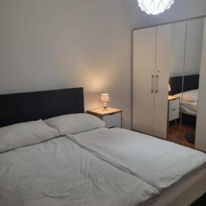 a bedroom with a white bed and a closet at Apartmani Katarina 4+2 in Biograd na Moru