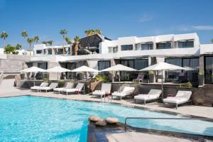 a hotel with a swimming pool with chairs and umbrellas at La Isla y el Mar, Hotel Boutique in Puerto del Carmen