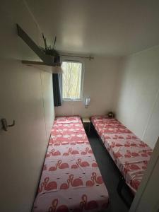 Duas camas num pequeno quarto com uma janela em Nette 4-persoons chalet aan het Lauwersmeer em Lauwersoog