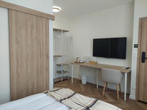 a bedroom with a desk and a television on the wall at Kwietny Stoczek 70 in Białowieża