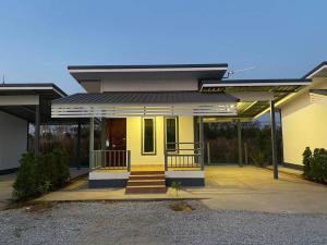 Casa amarilla con porche y escaleras en โรงแรมบ้านสวนวินเทจ en Ban Nam Mong