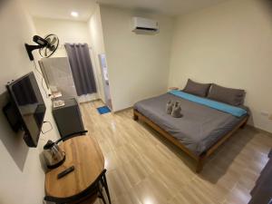 1 dormitorio con cama, mesa y TV en โรงแรมบ้านสวนวินเทจ en Ban Nam Mong