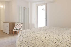 - une chambre blanche avec un lit et une chaise dans l'établissement Casa indipendente a due passi dal Centro Storico, à Saint-Marin