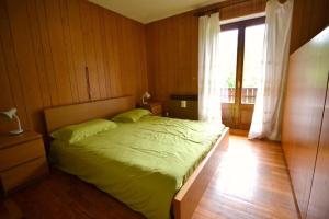 sypialnia z łóżkiem i dużym oknem w obiekcie Casa Faè Dolomiti w Madonna di Campiglio