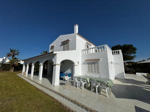 a white house with tables and chairs in front of it at Villa Savanna in Cala en Blanes