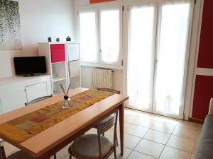 uma sala de jantar com uma mesa de madeira e algumas janelas em Appartamento Filippo em Castelnuovo del Garda