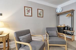 a room with two chairs and a table and a clock at Ranfield's Brasserie Hotel Rooms in Coggeshall