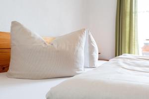 zwei weiße Kissen auf einem Bett mit Fenster in der Unterkunft Ferienwohnung Froböse in Reit im Winkl