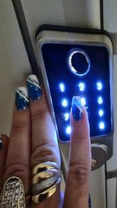 una mano con esmalte de uñas azul junto a un teléfono celular en Apartman Sekulić en Doboj