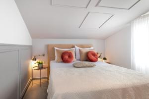 Schlafzimmer mit einem weißen Bett und roten Kissen in der Unterkunft DANICA Luxury SeaSide Apartment in Šibenik