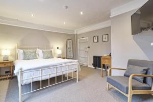 a bedroom with a bed and a chair at Ranfield's Brasserie Hotel Rooms in Coggeshall