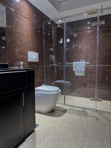 a bathroom with a toilet and a glass shower at Caesar Hotel in Muscat