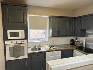 a kitchen with black cabinets and a sink and a window at Quaysiders Lakes Resort - Quaysiders Club in Ambleside