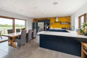uma cozinha e sala de jantar com mesa e cadeiras em Modern 4 Bed Bungalow - Peaceful Rural Setting Pass the Keys em Elstree