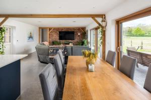 Il dispose d'une cuisine et d'un salon avec une table et des chaises en bois. dans l'établissement Modern 4 Bed Bungalow - Peaceful Rural Setting Pass the Keys, à Elstree