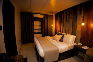 sypialnia z dużym łóżkiem z białą pościelą i poduszkami w obiekcie Vic & J Lounge and Hotel Asaba w Asabie