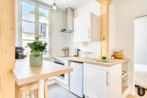 eine Küche mit weißen Schränken und einer Arbeitsplatte in der Unterkunft La Casa Relaxio — Un nid douillet en hyper centre in Caen