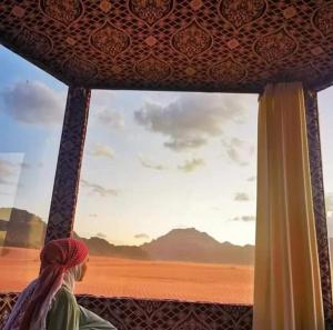 uma mulher a olhar pela janela do deserto em Mars moon camp em Wadi Rum