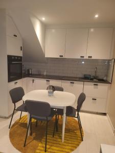 a white kitchen with a white table and chairs at Hanaborg apartment in Lorenskog