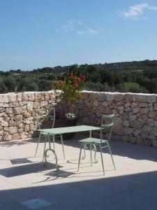a table and two chairs sitting next to a stone wall at Antica Masseria San Benedetto in Ostuni