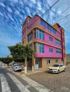 un edificio rosa con macchine parcheggiate di fronte di Zeyden Place Apt 2 a Praia