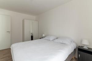 een slaapkamer met een wit bed met 2 kussens bij Moulin à Vent Nord - Appt à 20 minutes de Paris in Bondy