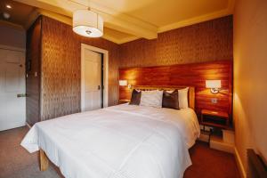 1 dormitorio con 1 cama blanca grande y paredes de madera en Old Orleton Inn en Wellington