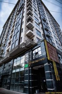 un edificio alto con un cartel delante en «Casamia» апартаменты с 2 спальнями, en Bishkek