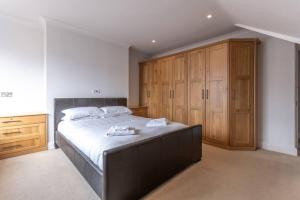 a bedroom with a large bed and wooden cabinets at Pass the Keys Large and spacious House in Chelmsford in Chelmsford