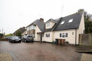 a house with two cars parked in a parking lot at Pass the Keys Large and spacious House in Chelmsford in Chelmsford