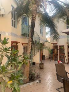 a courtyard with a palm tree in front of a building at Sumanguru Guest House- GATEWAY TO THE AIRPORT in Busumbala