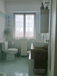 a bathroom with a toilet and a sink and a window at Appartamento a 50 mt dal mare in Rosignano Solvay