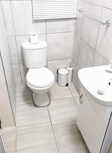 a white bathroom with a toilet and a sink at Cozy Corner in Groblersdal