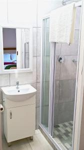 a white bathroom with a shower and a sink at Cozy Corner in Groblersdal