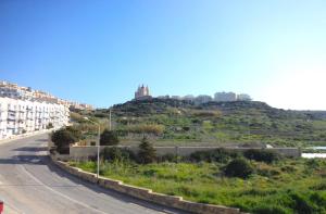 an empty street with a hill with buildings on it at Seafront apartment Terrace, lounger & Panoramic ocean views in Mellieħa