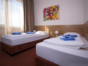 two beds in a hotel room with towels on them at Aviator Garni Hotel Bratislava in Bratislava