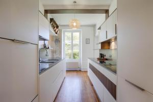 uma cozinha com armários brancos e piso em madeira em La Villa Océane — Beach & old presbytery em Lion-sur-Mer