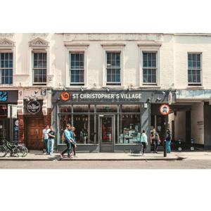 a group of people walking on a street in front of a store at St Christopher's Inn Village - London Bridge in London