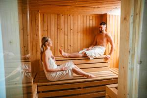 a man and woman sitting in a sauna at Vila Emma in Vysoke Tatry - Strbske Pleso