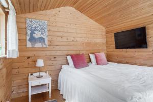 a bedroom with a bed with a tv on the wall at Cosy Cottages Close To Water in Djurhamn