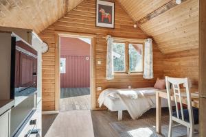 Cabaña de madera con cama, mesa y TV en Cosy Cottages Close To Water en Djurhamn