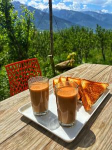 un plato con dos vasos de café y pan en una mesa en Kihala Homestay, en Manali