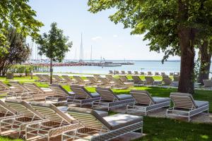 a row of chairs sitting on the grass near the water at LUA Resort - Adults only in Balatonfüred