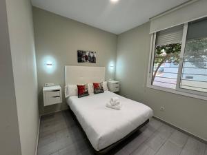een kleine slaapkamer met een wit bed en een raam bij Garden City Lofts in Córdoba