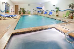 una piscina en un hotel con sillas azules y una piscina en Holiday Inn Express & Suites Fort Worth - Fossil Creek, an IHG Hotel, en Fort Worth