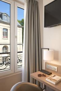 Cette chambre dispose d'un bureau et d'une fenêtre avec une table et des chaises. dans l'établissement Timhotel Paris Gare de l'Est, à Paris