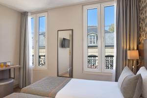 パリにあるティムホテル ガル ドゥ レスト（旧 ア ラ ヴィラ サン マルタン）のベッドと大きな窓が備わるホテルルームです。
