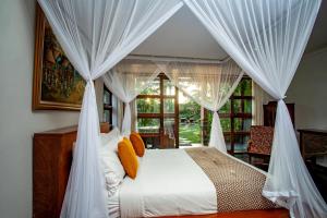a bedroom with a canopy bed with white curtains at Aryaswara Villa Ubud in Ubud